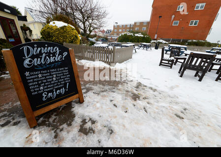 I visitatori del Toby Carvery a Thorpe Bay, Southend on Sea, hanno la possibilità di mangiare fuori, nonostante il tempo con la neve su tavoli e sedie Foto Stock