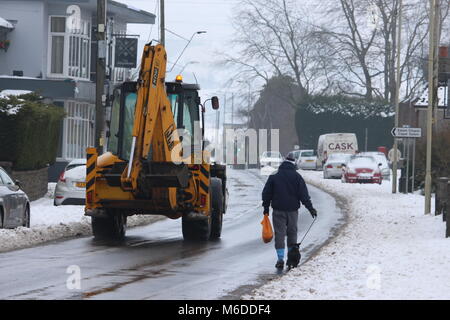 Llantwit Fardre, pontypridd, Wales, Regno Unito - 03 Marzo 2018: Un uomo cammina il suo cane a casa da un negozio lungo un nevoso, viscido street, come un trattore aziona passato. Credito: Elizabeth Foster/Alamy Live News Foto Stock