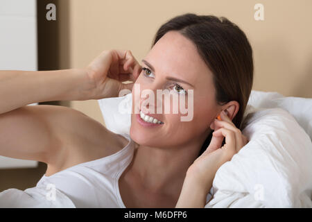 Close-up di un felice giovane donna inserimento tappo per orecchie In Her Ear Foto Stock