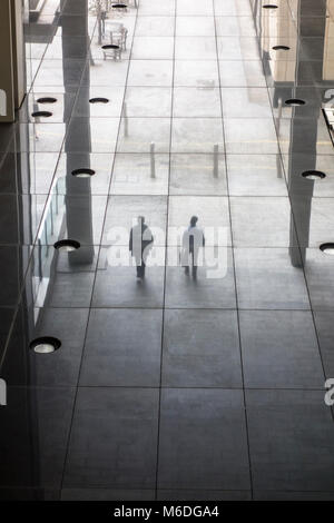 La riflessione di due persone a piedi in un ambiente cittadino Foto Stock