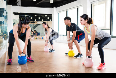 Professional Asian fitness trainer come insegnamento per fare kettlebell con il team del discente in palestra. Foto Stock