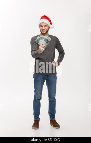 Concetto di vacanza - barba giovane uomo in maglione che mostra i soldi per telecamera. Foto Stock