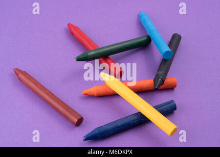 Alcune cere colorate matite colorate su una superficie di colore blu Foto Stock