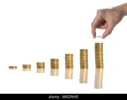 Mano azienda e aggiunta di una moneta d'oro sulle pile di monete d'oro con sementi su sfondo bianco, business Concetto di investimento Foto Stock