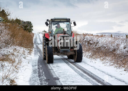 Irish Farmer nel trattore Massey Ferguson 390T nella neve sul paese lane, Valentia Island, nella contea di Kerry, Irlanda Foto Stock