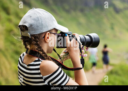 12 anno vecchia ragazza di scattare foto con una lente a lungo in un meraviglioso paesaggio di scogliere irlandese Foto Stock