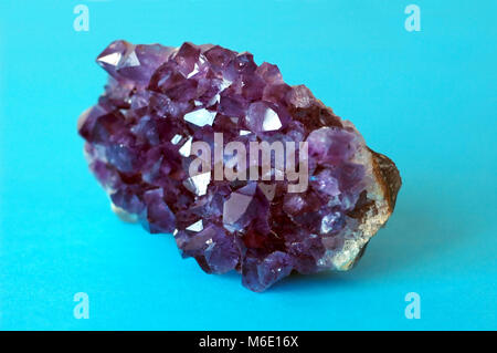 Viola ametista grezzo cristallo su sfondo blu Foto Stock