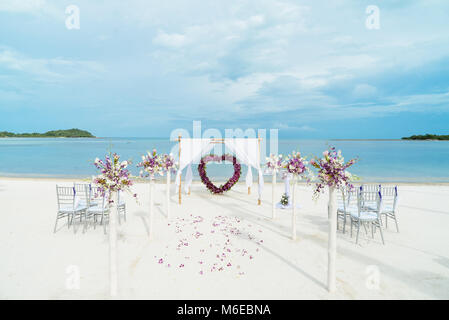 I matrimoni di piccole dimensioni con decor di rose e fiori a forma di cuore, petali sul corridoio, vista sull'oceano e cielo chiaro Foto Stock