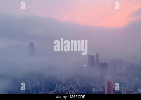 I foggy skyline di Hong Kong. Molti edifici sono coperti quando visto dalla vetta. Solo i più alti grattacieli possono avere la loro parte superiore visibile. Foto Stock