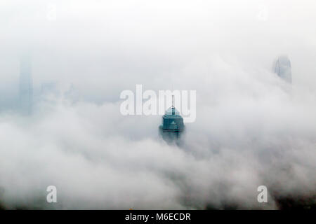 I foggy skyline di Hong Kong. Molti edifici sono coperti quando visto dalla vetta. Solo i più alti grattacieli possono avere la loro parte superiore visibile. Foto Stock