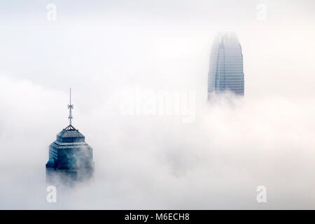 I foggy skyline di Hong Kong. Molti edifici sono coperti quando visto dalla vetta. Solo i più alti grattacieli possono avere la loro parte superiore visibile. Foto Stock