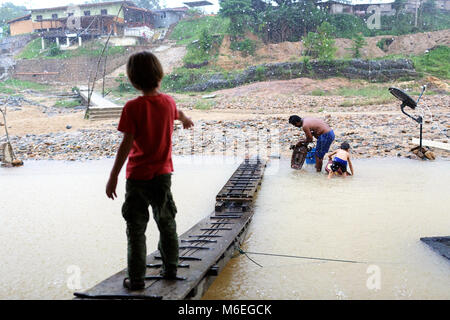 Giovane turista che guarda un padre e un figlio locali che puliscono le parti del motore della barca nel fiume dal ristorante della barca, Kuala Tahan, Taman Negara National P. Foto Stock