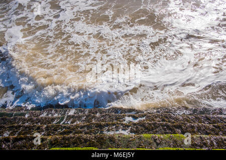 L alta marea sul percorso sul lungomare vicino a Broadstairs con il mare lambisce il promenade passi per la spiaggia sabbiosa. Foto Stock