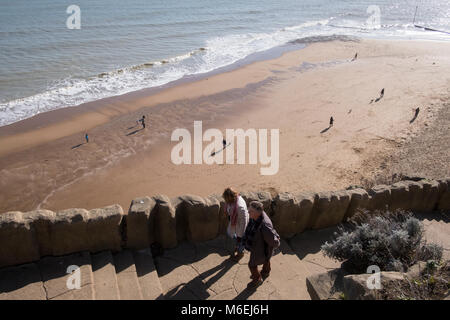 La gente a piedi sulla spiaggia sabbiosa con i loro cani e fino alla scogliera passi a Ramsgate come la marea si ritira. Foto Stock