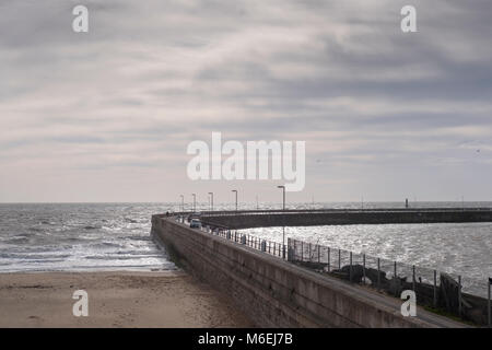 Le persone camminano sulla parete porto strada come la marea entra in una giornata di sole a Ramsgate Kent Foto Stock