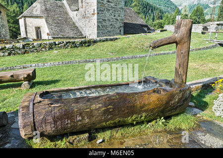 Tradizionale in legno fontana di acqua nelle montagne, in un piccolo villaggio delle Alpi Foto Stock