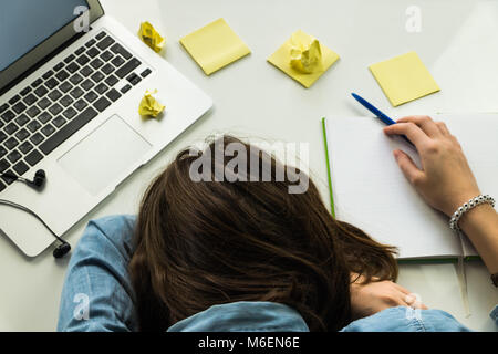 Stanco persona che dormiva a casa scrivania in ufficio Foto Stock