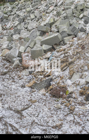 Pila di builder / macerie con una spolverata di neve presente. Metafora per la rotta in pezzi, a brandelli, frantumata in pezzi Foto Stock