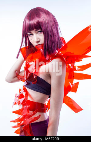 Donna asiatica cosplayer con costume futuristico in rosso, realizzata con plastica pvc e lucidi. Ragazza orientale Foto Stock