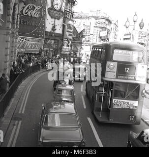 Anni sessanta, foto storiche che mostra i veicoli a motore, comprese le automobili, taxi e autobus Routemaster, dirigendosi verso un affollato Piccadilly Circus, gremito di gente, Londra, Inghilterra, Regno Unito. Foto Stock