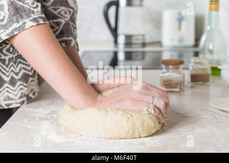 Close-up di preparazione e miscelazione della pasta. Mani femminili gli impasti in una moderna cucina minimalista. Foto Stock