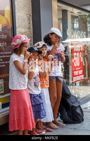 Vanne, Farnce. Un gruppo di bambini di sostare dietro un esecutore di strada fingendo di giocare a strumenti musicali Foto Stock