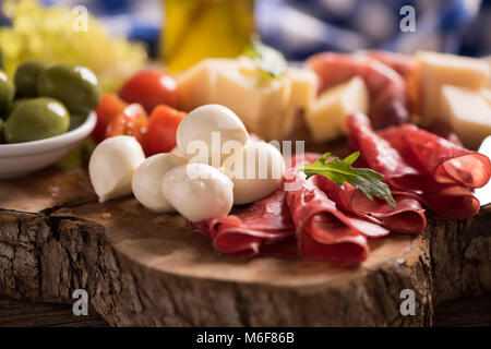 Un assortimento di salumi e di un piatto di formaggio, su di un tagliere di legno. Antipasti italiani Foto Stock