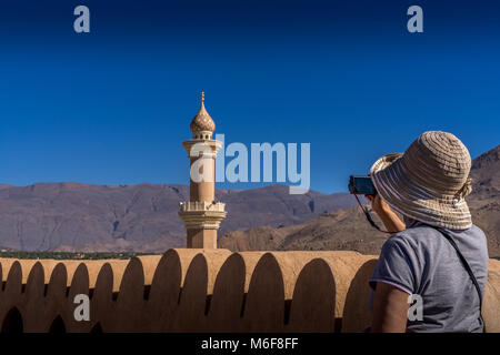 La donna sta immagine del minareto della moschea dal forte di Nizwa; annuncio Dakhiliyan, Oman Foto Stock