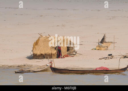 Una vista del fiume Irrawaddy in Myanmar Birmania con un pescatore del capanno sulle rive del fiume e una piccola barca nel fiume Foto Stock