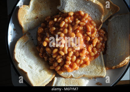 Una pila di fagioli su pane tostato con scaglie di peperoncino spruzzato sulla parte superiore come un pranzo snack. Foto Stock