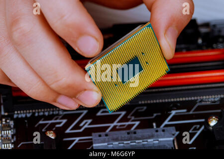 Il tecnico sta mettendo la CPU sullo zoccolo della scheda madre del computer. il concetto di hardware del calcolatore, riparazione Foto Stock