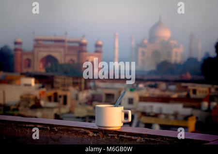 La tazza di tè sullo sfondo del Taj Mahal più famoso punto di riferimento. La colazione sul tetto di un edificio in Agra. India. Foto Stock