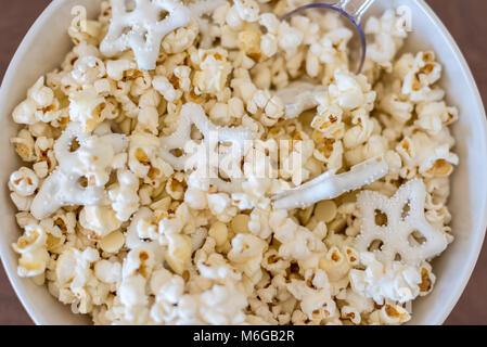 Overhead closeup di inverno popcorn a tema con il cioccolato bianco pretzel nel recipiente Foto Stock