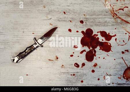 Immagine concettuale di un coltello affilato con il sangue su di essa appoggiato su un pavimento di calcestruzzo. Concetto foto di omicidio e la criminalità Foto Stock