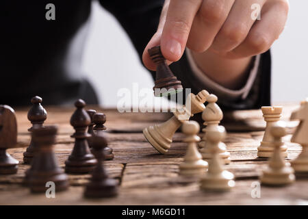 Close-up di un imprenditore Checkmating re pezzo degli scacchi con Rook sulla scrivania in legno Foto Stock