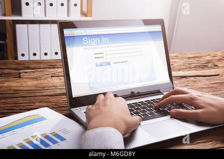 Close-up di un imprenditore della firma a mano nel sito Web sul computer portatile in ufficio Foto Stock