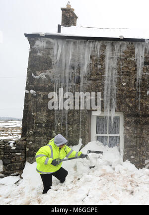 Mags Turnbull da Browfoot cottage in Bowerdale in Cumbria scava se stessa dopo essere stato nevicato per tre giorni come il freddo in tutto il paese continua. Foto Stock