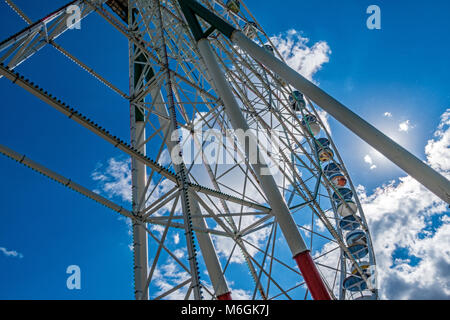 Enorme ruota panoramica contro il cielo nuvoloso nel parco divertimenti con vista dall'angolo basso Foto Stock