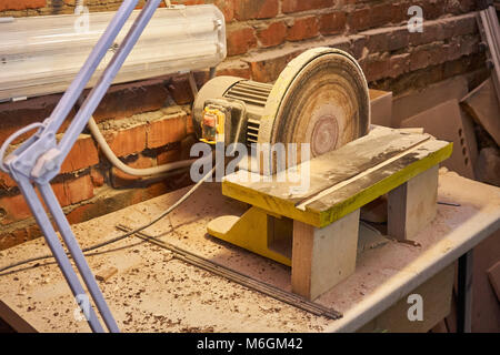 Levigatrice a disco da banco con lampada nella polvere dopo il lavoro in officina Foto Stock