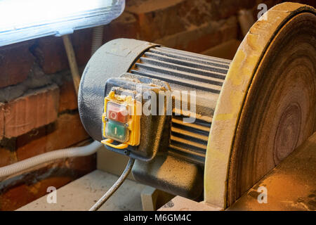 Levigatrice a disco da banco con lampada nella polvere dopo il lavoro in officina Foto Stock