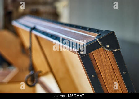 Robusto torace in teak con molla a gas di sollevamento. Cassettiera aperta in legno in teak massiccio, legno compensato e struttura in metallo vista closeup estrema Foto Stock