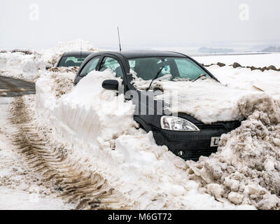 East Lothian, Scozia, Regno Unito, 4 marzo 2018. Regno Unito Meteo: due vetture sepolto nella neve sul Drem a Haddington Road dopo la nevicata come risultato delle condizioni meteorologiche estreme evento, soprannominato il "Bestia da est. Alta banchi di neve crea un passaggio stretto Foto Stock