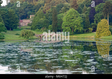 Guardando attraverso la Stourhead Garden lago al ponte palladiano e la chiesa di San Pietro Foto Stock