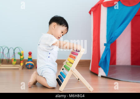 Asian bimbo impara a contare. Carino bambino che gioca con abacus giocattolo. Little Boy divertirsi al chiuso in casa. Il concetto educativo per il bambino. Foto Stock