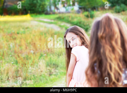 Giovane e bella ragazza con lunghi capelli bruna, guardando alla telecamera al giorno d'estate. Divertimento di gioiosa kid. Posto per il testo Foto Stock