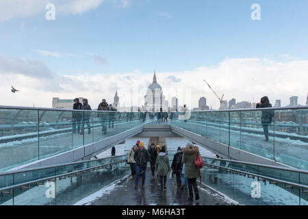Persone che indossano un abbigliamento caldo attraversando a piedi il millennio (traballanti) ponte vicino alla Cattedrale di St Paul durante una fredda giornata invernale e. Foto Stock