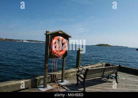 Vita anello vicino a sedile sul fronte mare Halifax Nova Scotia Shore anello isola acqua seduta panca corda corde pericolo fuori calma legno pesca estate Foto Stock