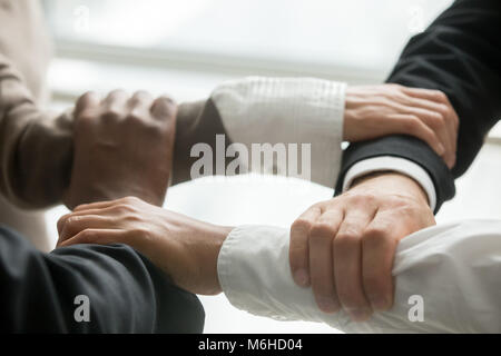 Quattro multirazziale la gente di affari azienda ogni altri polsi, clo Foto Stock