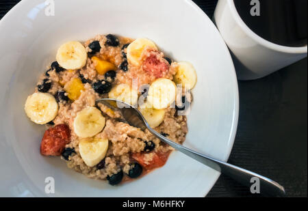 Farina di avena con frutta mista e una tazza di caffè nero Foto Stock