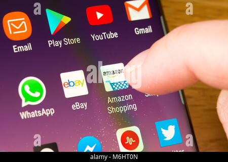 Primo piano dell'app Amazon Shopping su uno smartphone selezionato dal dito di una donna che punta sull'app lo schermo del telefono cellulare Foto Stock